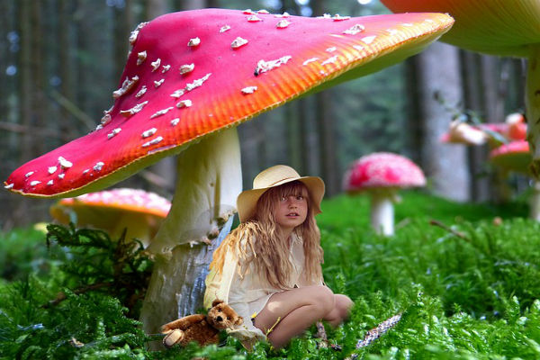 girl sitting under giant mushroom